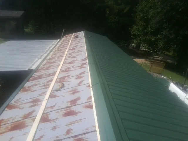 Old rusted panels beside newly installed green metal roofing — Wind Damage Roof Repair by Roofing Brothers in Bourneville