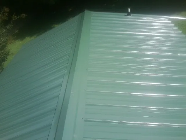 New green metal panels meeting at the ridge of a roof — Flat Roof Repair work by our crew in Bourneville