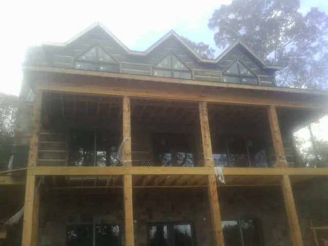 Dormers and porch framing on a large log home under construction — Roof Coating work by our crew in Bourneville