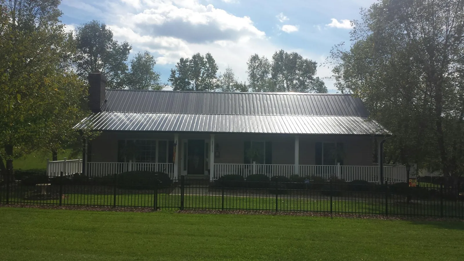 Gray metal roof on a brick ranch with a full width front porch — Gutter Guard Installation work by our crew in Bourneville