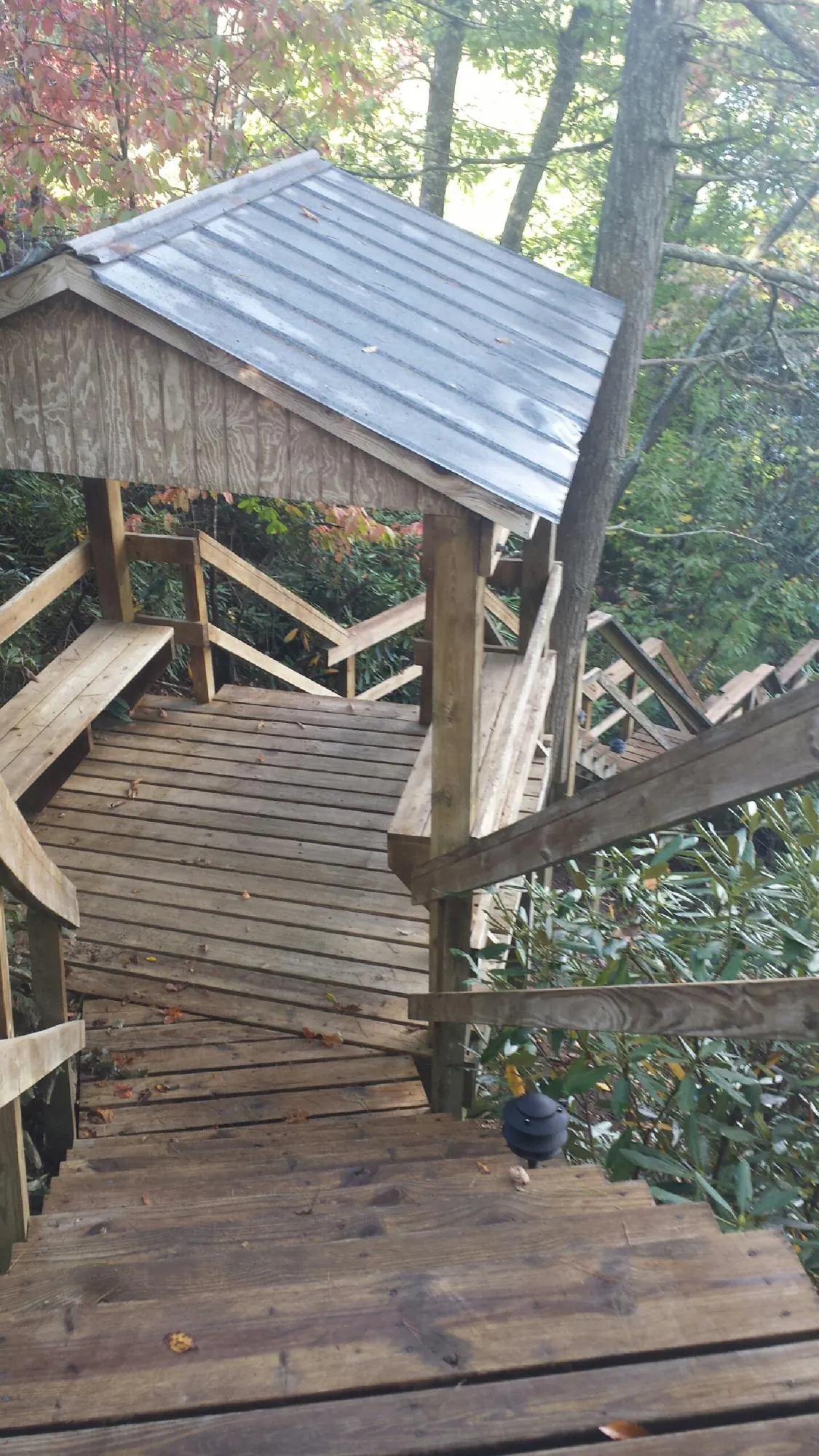 Metal roofed shelter over wooden steps on a wooded walkway — Skylight Repair & Installation work by our crew in Bourneville