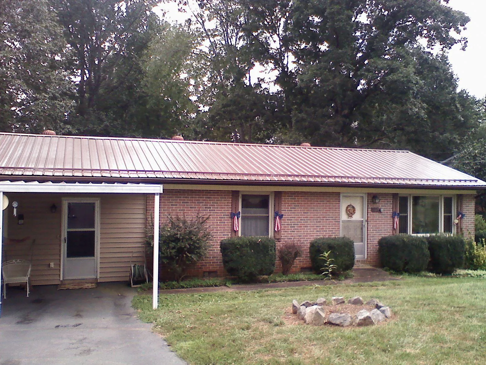 Bronze metal roof and carport on a brick ranch home — Roof Repair work by our crew in Bourneville