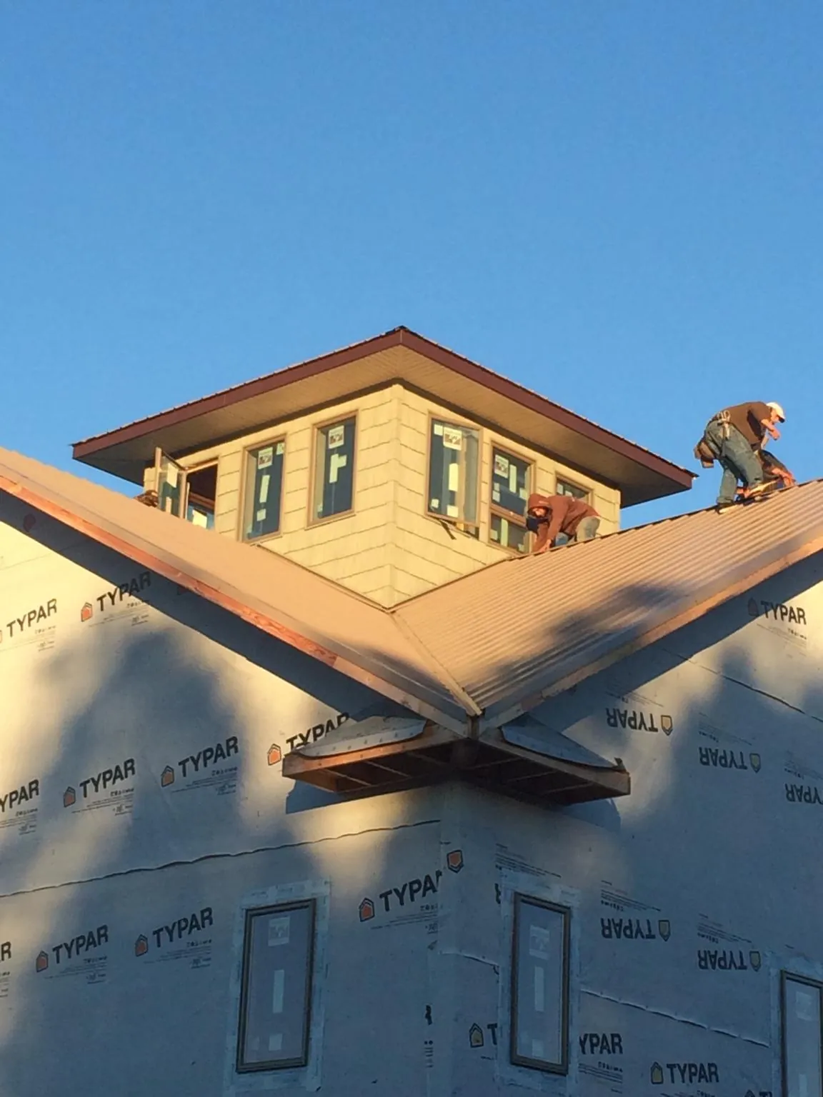 Roofers working around a rooftop cupola on a new metal roof at sunset — Roof Waterproofing in Bourneville by Roofing Brothers